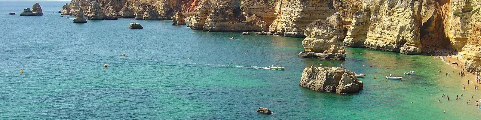 Golden limestone cliffs and sea stacks above turquoise water at Praia de Dona Ana, Lagos, on the Algarve coast