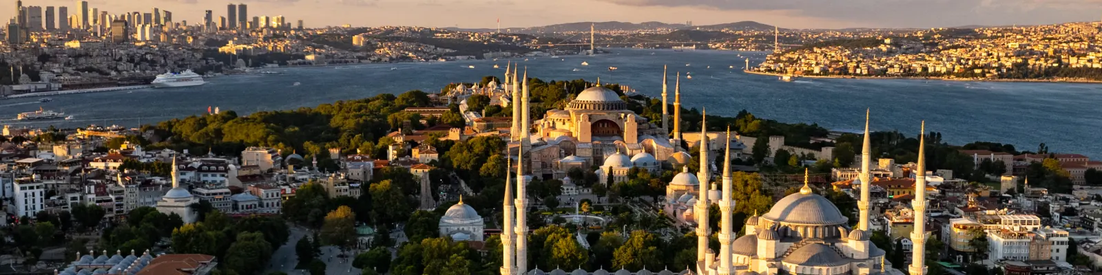 The Blue Mosque and Hagia Sophia in golden evening light, the Bosphorus and the Asian shore of Istanbul beyond